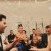 Bride and groom celebrating at a lively indoor wedding reception with friends and family.
